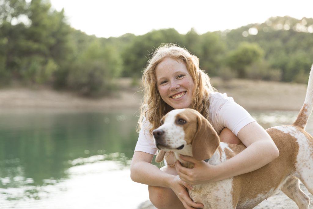 woman smiling and hugging a dog