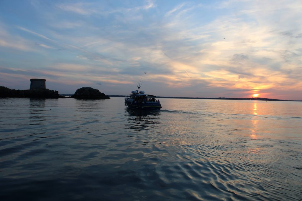 boat sailing on the sea with sun setting in background